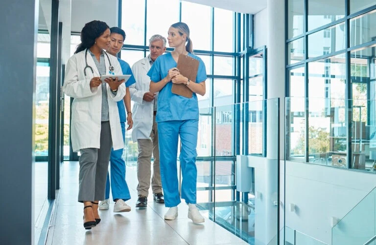 Healthcare professionals collaborate in a modern hospital corridor discussing patient care and treatment strategies