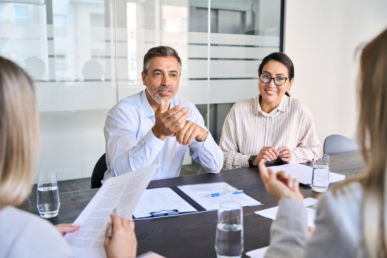 Diverse executive team engaging in a board meeting discussing project management and strategies in a modern office setting