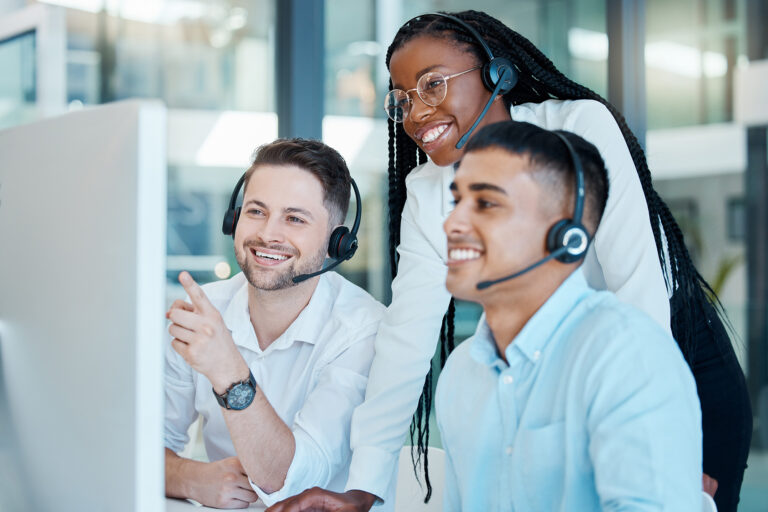 Diverse customer service team in a call center happily engaging with feedback and sales on a computer