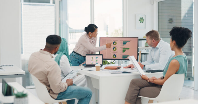 Business team engaged in a presentation reviewing financial graphs and KPIs on screens focused on strategic planning in a modern office