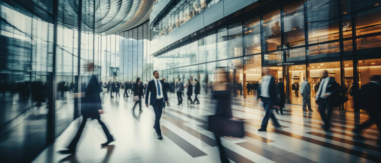 Blurred business professionals in a modern glass office setting representing the dynamics of a shared services organization