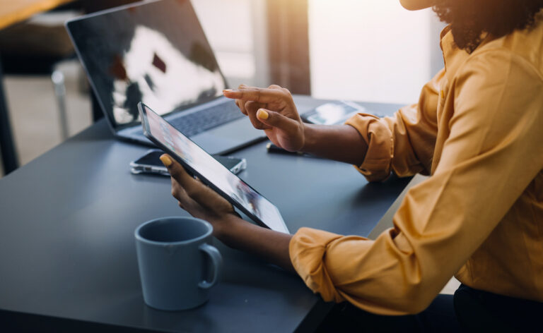Young woman using a tablet for financial analysis in a modern office emphasizing effective BYOD strategies and remote work