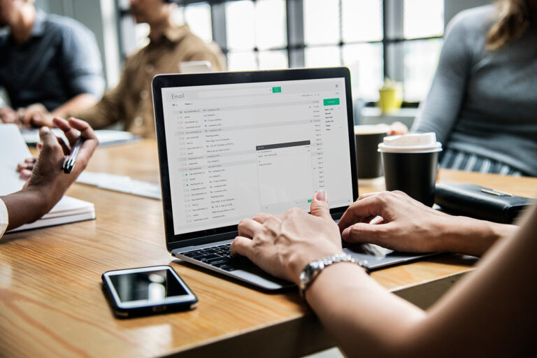 Woman checking email on a laptop during a meeting focusing on Office 365 email migration strategies