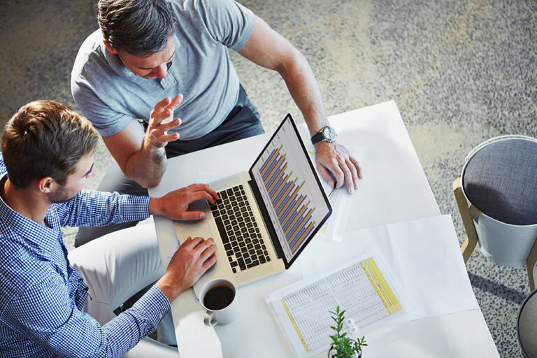 Business team analyzing data on a laptop discussing statistics and chart analytics for effective month end close processes