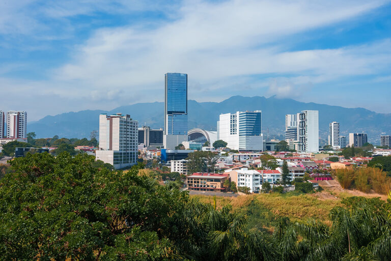 Panoramic view of San Jose Costa Rica showcasing modern buildings against a backdrop of mountains and blue sky