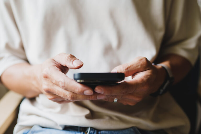 Person focused on mobile phone illustrating the impact of online social engagement and digital communication habits