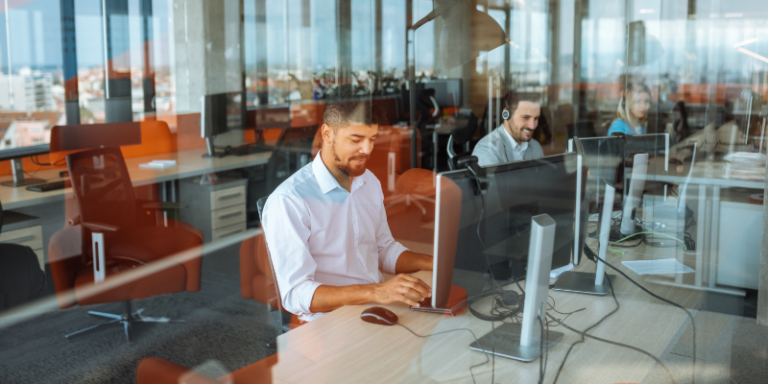 Office scene featuring professionals at help desk workstations illustrating dedicated vs shared services models for businesses