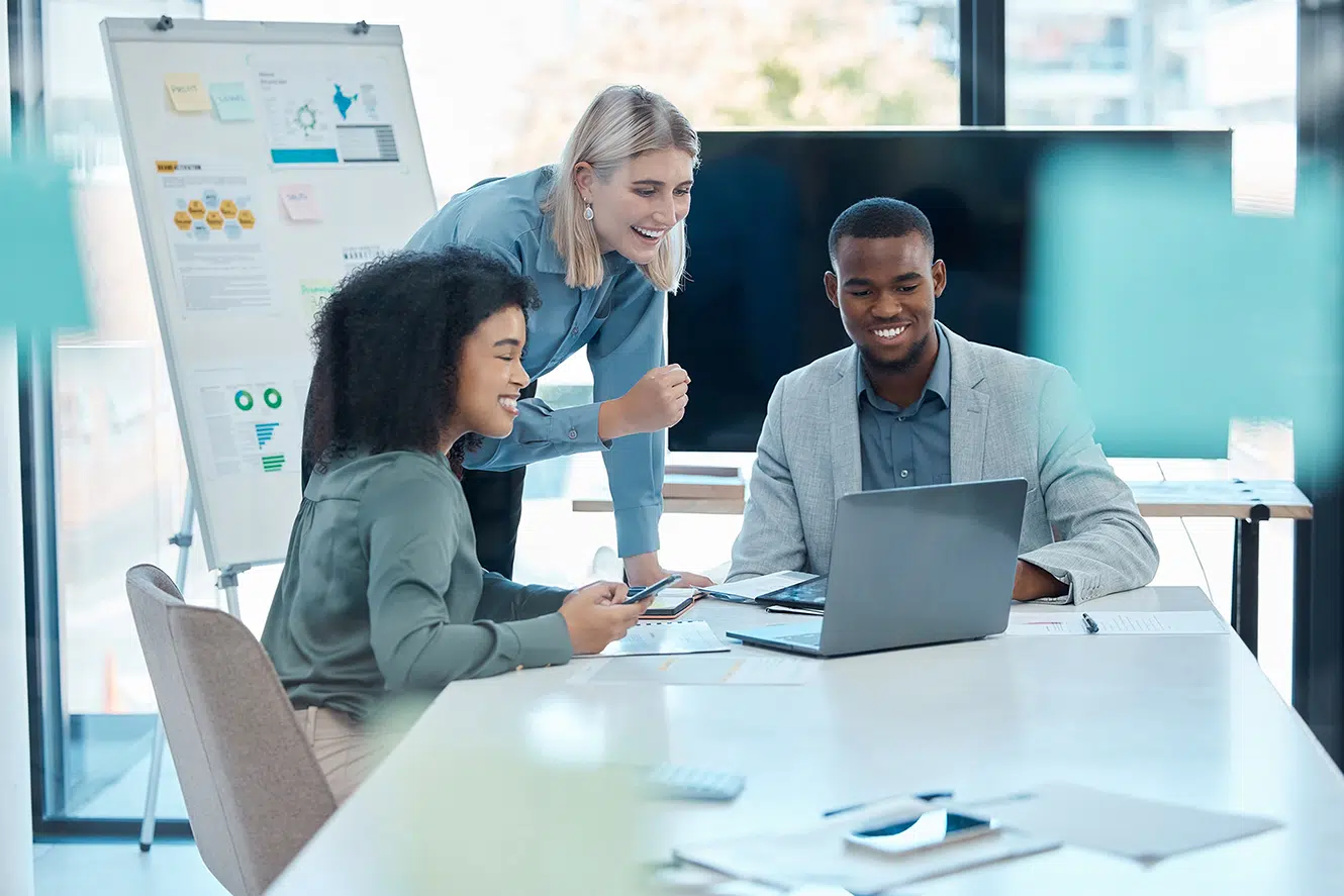 Team gathered around a laptop in a modern office setting collaborating on deduction management strategies to improve accounts receivable deductions and AR deductions processes