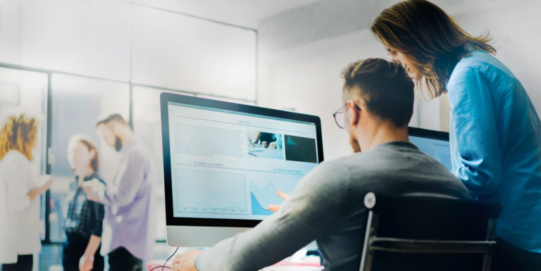 Two professionals collaborate on a computer in a bright office analyzing data related to optimizing the NetSuite accounts payable process