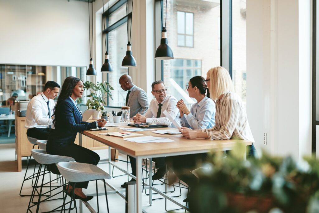 A diverse team collaborates at a modern workspace discussing HR outsourcing strategies with laptops and documents on the table