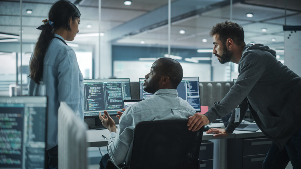 Three cybersecurity workers debating in front of a computer
