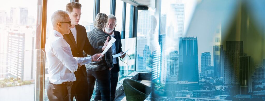 Business professionals collaborate in a modern high rise discussing strategies with a city skyline backdrop