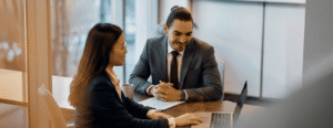 Two professionals engaged in a positive discussion over a laptop in a modern office setting emphasizing collaboration