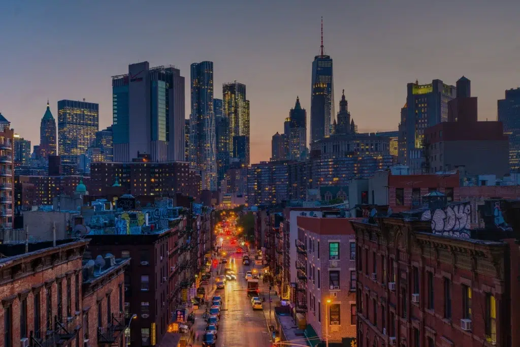 A view of a city at dusk with tall buildings and city lights in the background
