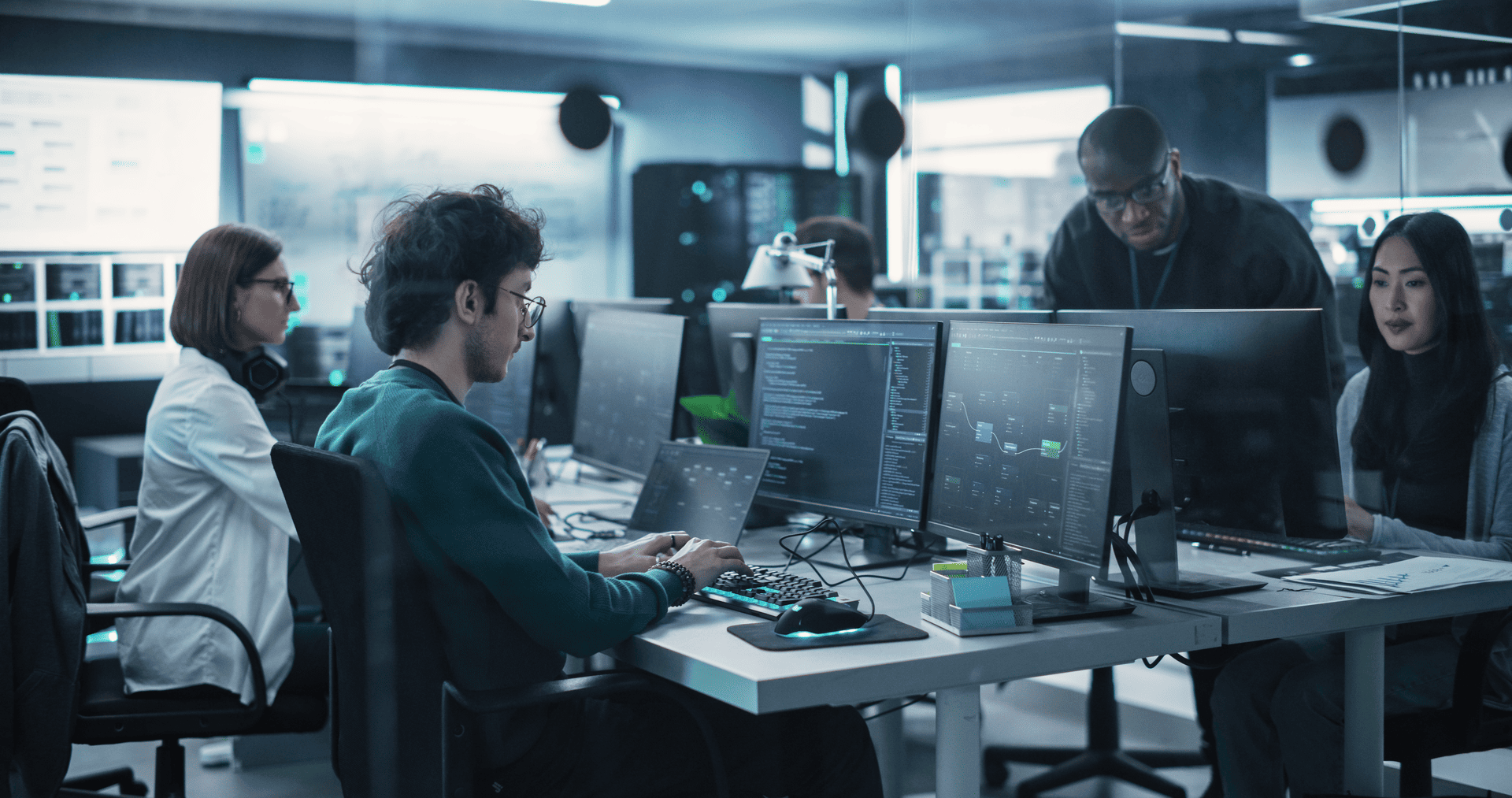 A team of professionals collaborating in a cybersecurity operations center with multiple monitors displaying security data