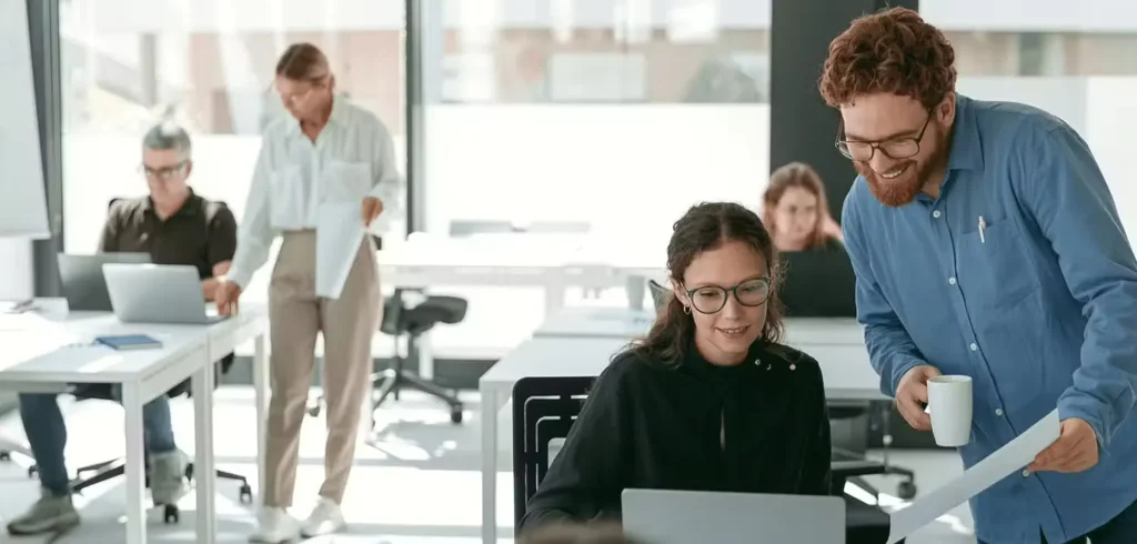 Collaborative workplace scene with team members engaged in discussion and teamwork at modern office desks