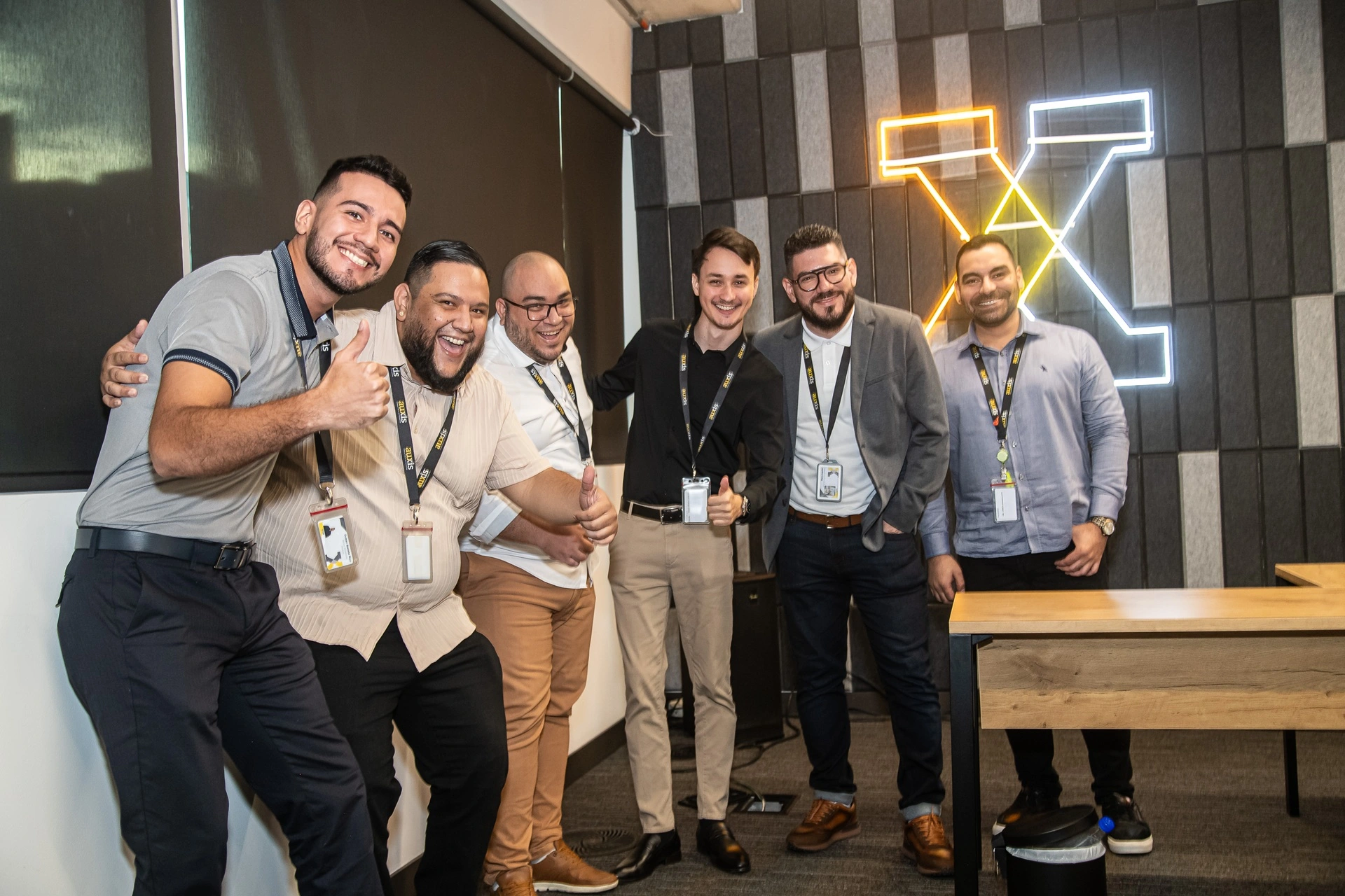 A diverse group of six professionals smiling and posing together in a modern office setting showcasing teamwork and camaraderie