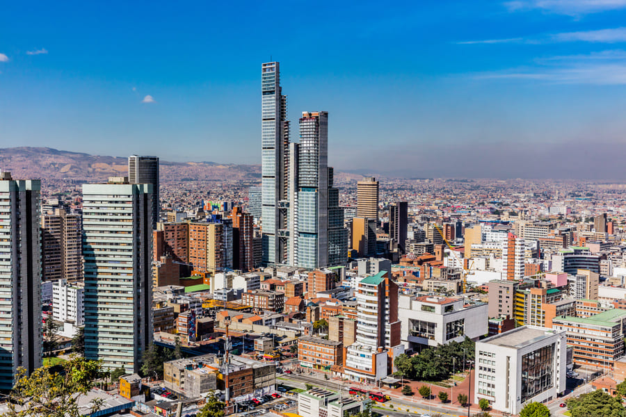 Skyline of BogotĆ” featuring modern skyscrapers amidst a bustling urban landscape under a clear blue sky.