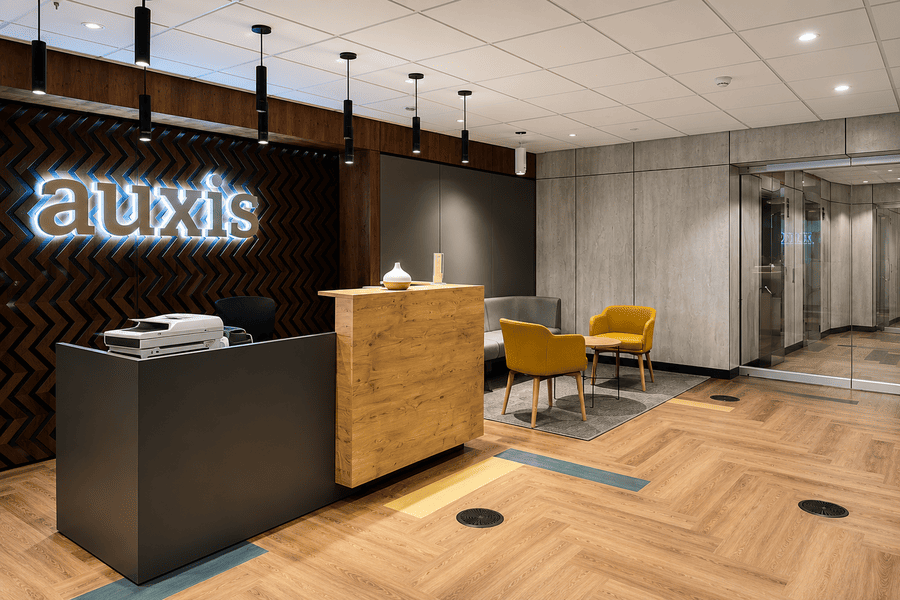 Modern reception area with wooden accents and bright yellow chairs, showcasing a welcoming atmosphere for Auxis.