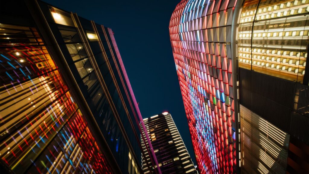 Vibrant cityscape at night showcasing modern architecture with colorful illuminated facades reflecting urban innovation
