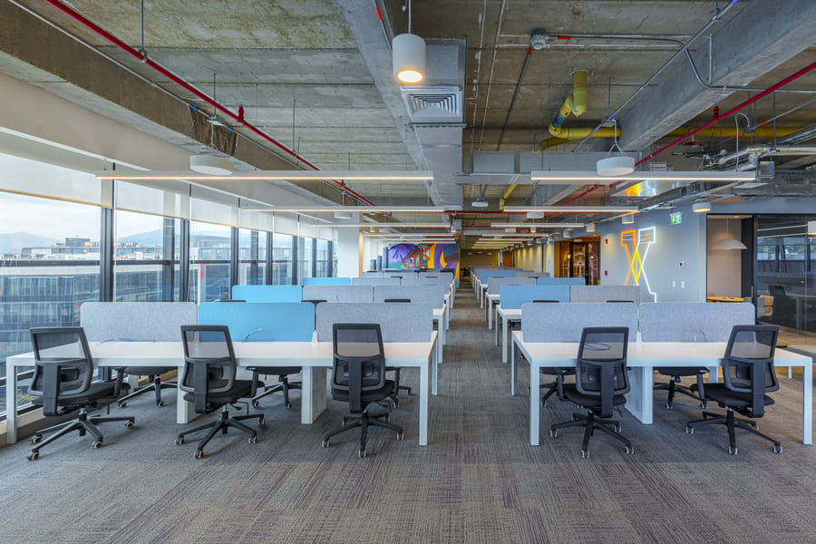 Modern office workspace featuring rows of desks with ergonomic chairs, designed for collaborative productivity.
