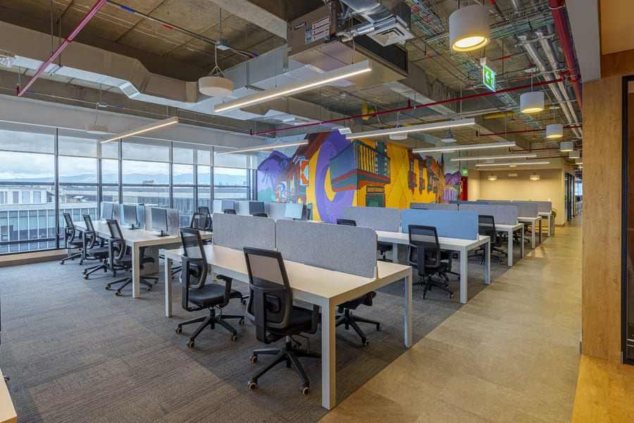 Modern office space featuring collaborative workstations and vibrant wall art, promoting creativity and productivity.