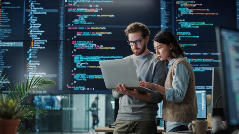 Collaborative software developers analyze code on a laptop showcasing AI powered outsourcing in action