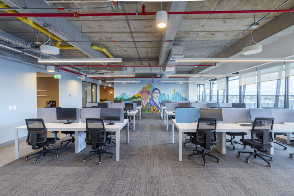 Solinoff - Auxis-38 1 1 - Auxis Modern office space featuring collaborative workstations and a vibrant mural reflecting Auxis' growth in Bogotá.