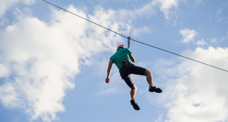 a man descends on a rope, a sport in an extreme park, A man walking along a zip line,