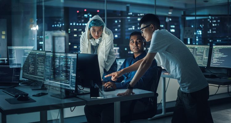 Diverse Team of Professionals Meeting in Office at Night: Brainstorming IT Programmers Use Computer Together, Talk Strategy, Discuss Planning. Software Engineers Develop Inspirational App Program