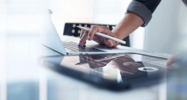 Hand with a digital pencil on a computer and tablet