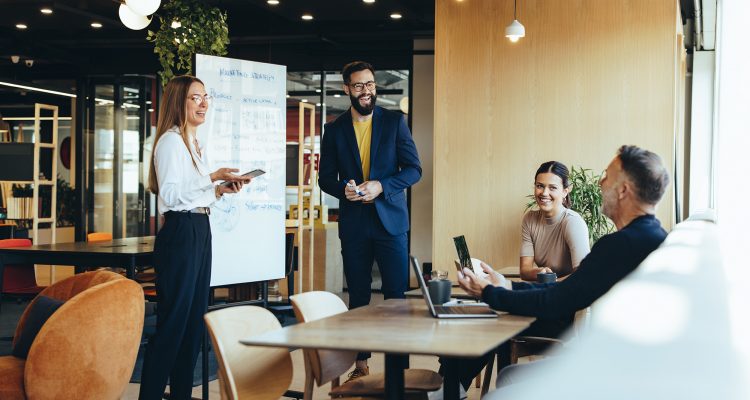 Cheerful businesspeople having a discussion during a meeting in a modern workspace. Two happy young entrepreneurs presenting their marketing strategy and ideas to their colleagues.